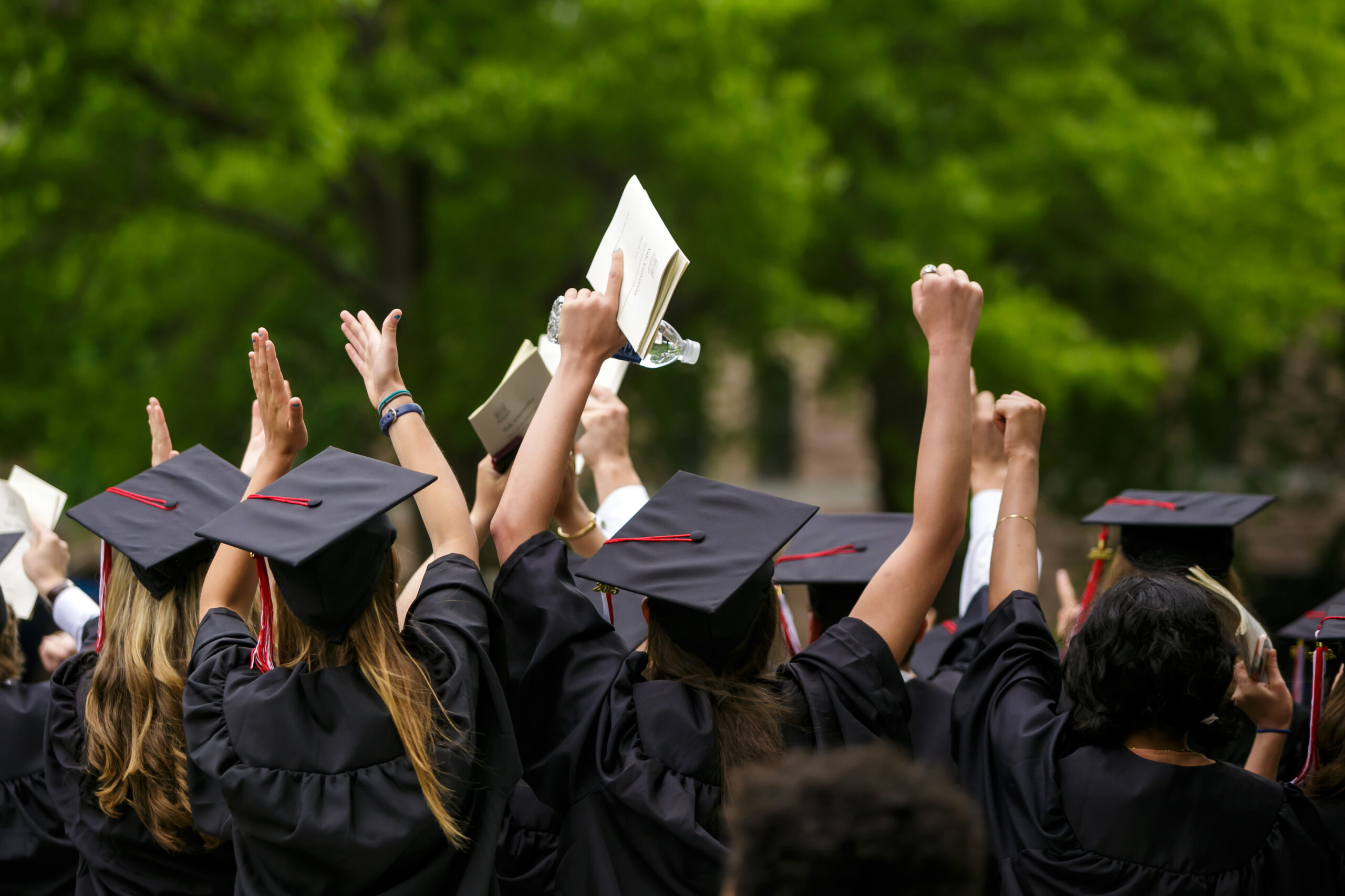 A group of new grads celebrating with their hands raised